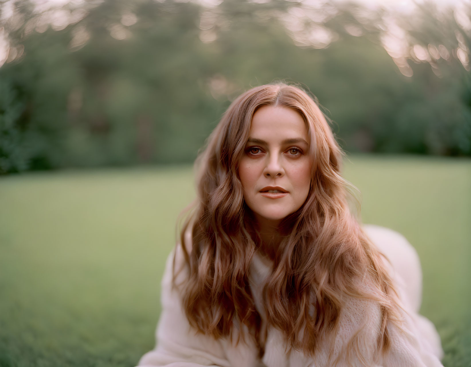 Long-Haired Woman in White Top Outdoors with Blurred Green Background