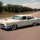 Cream-Colored Vintage Car Driving with Person Inside, Trees and Blue Sky in Background