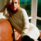 Woman in White Sweater Poses on Leather Chair with Mountain View