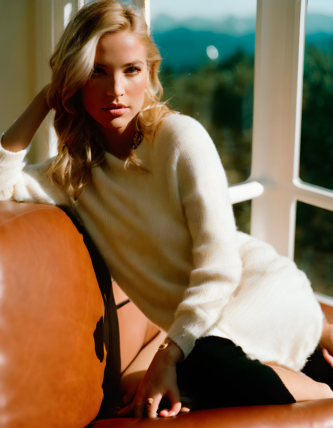 Woman in White Sweater Poses on Leather Chair with Mountain View