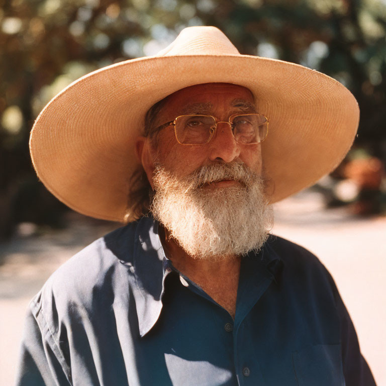 Elderly Man with Beard and Straw Hat Outdoors in Blue Shirt