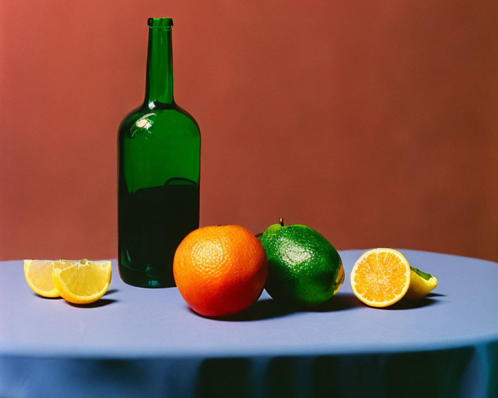 Green bottle with orange, lime, and lemon slices on blue tabletop and peach backdrop