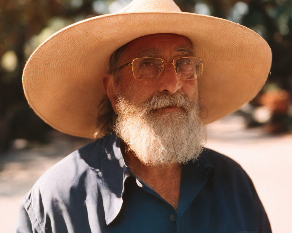 Elderly Man with Beard and Straw Hat Outdoors in Blue Shirt