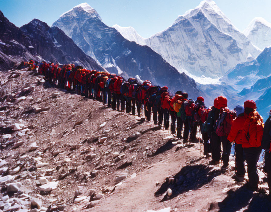 Group of Climbers in Red Jackets Scaling Snowy Mountain Trail