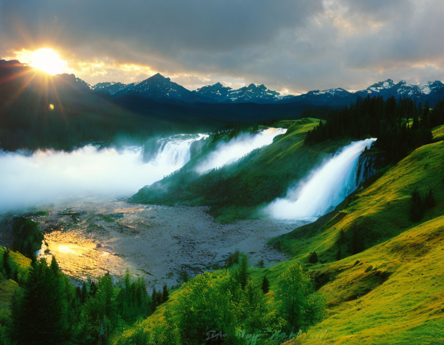 Scenic sunset view of majestic waterfall, mist, grassy slopes, and mountains.