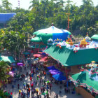 Christmas-themed theme park with festive decorations and palm trees bustling with visitors under sunny sky