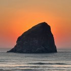 Surreal iceberg with archway under giant setting sun