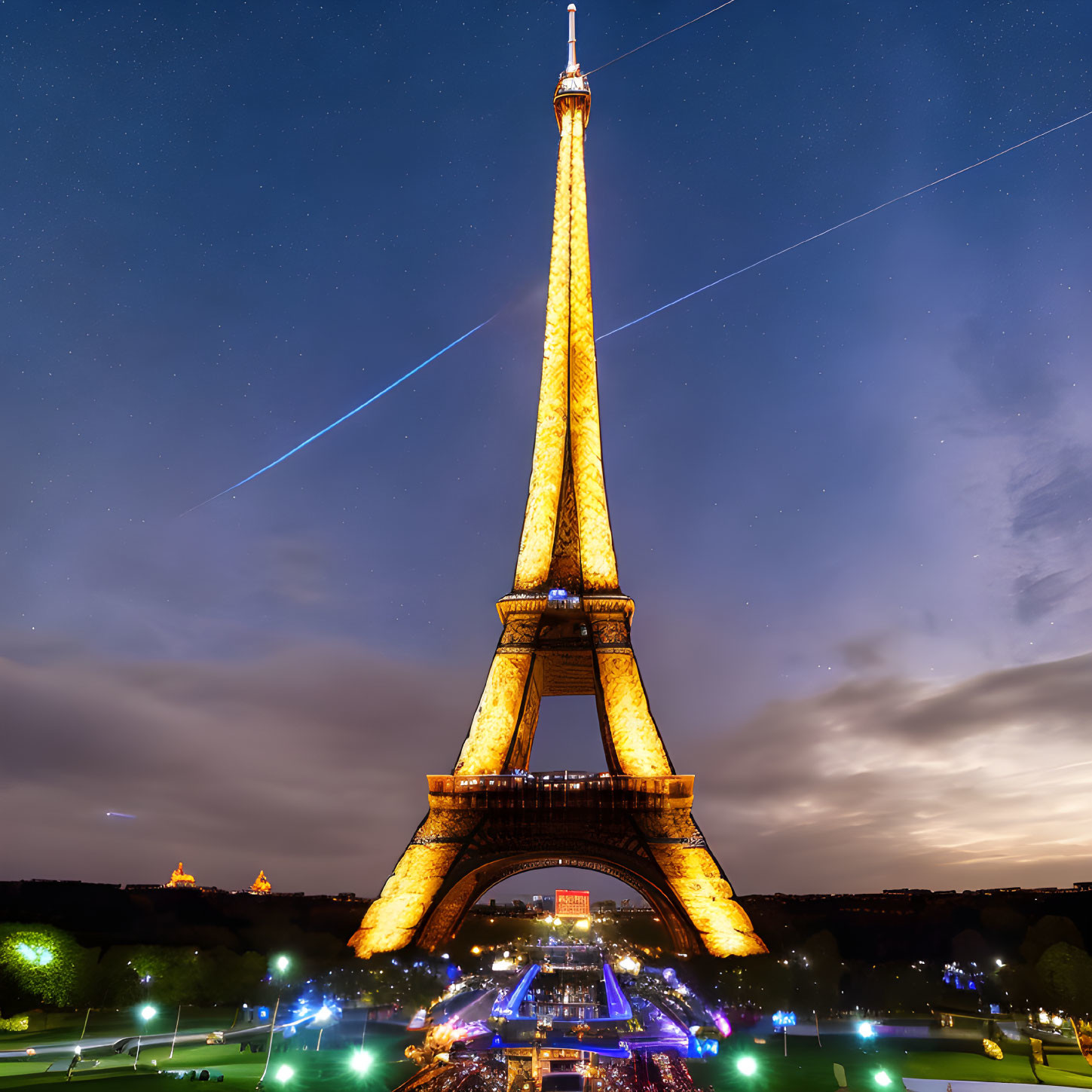 Iconic Eiffel Tower Night View with Passing Aircraft Streaks