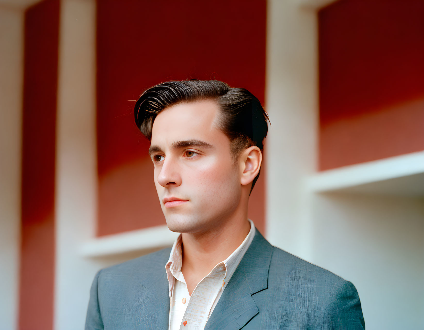 Young man in grey suit against red and white abstract backdrop