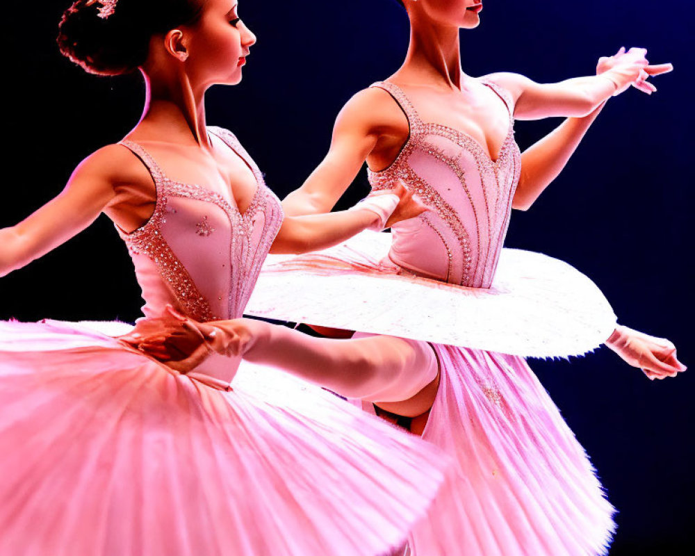 Two ballet dancers in pink tutus and tiaras pose against a deep blue background