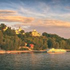 Tranquil lake, lush forest, castle on hill in warm sunlight