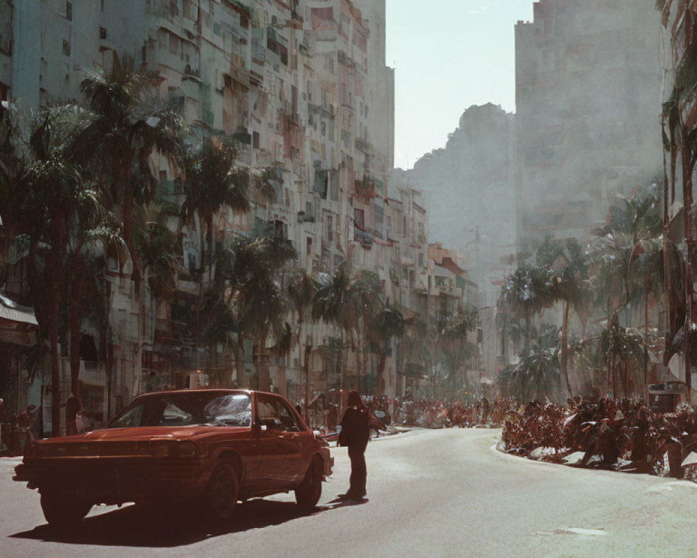 Vintage Red Car Driving on Sunlit City Street with High-Rise Buildings and Parked Motorcycles