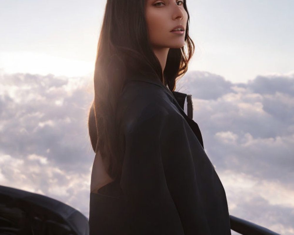 Woman in black outfit gazing over shoulder at twilight clouds.