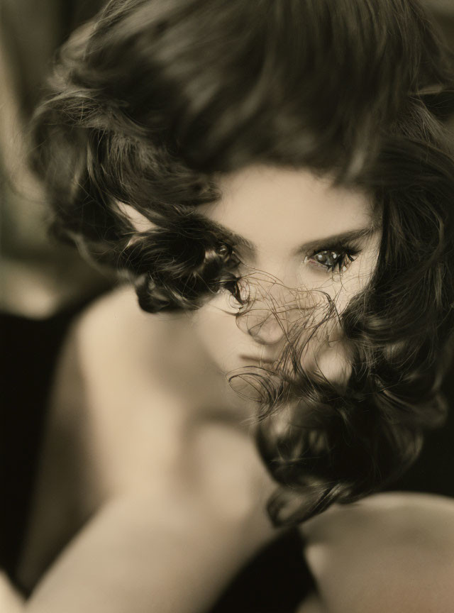 Monochrome close-up photo of person with curly hair and intense gaze