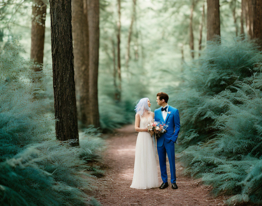 Bride with lilac hair and groom in blue suit in forest setting