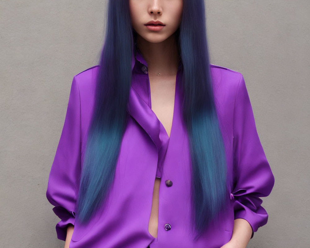 Blue-haired person in purple satin blouse against grey background