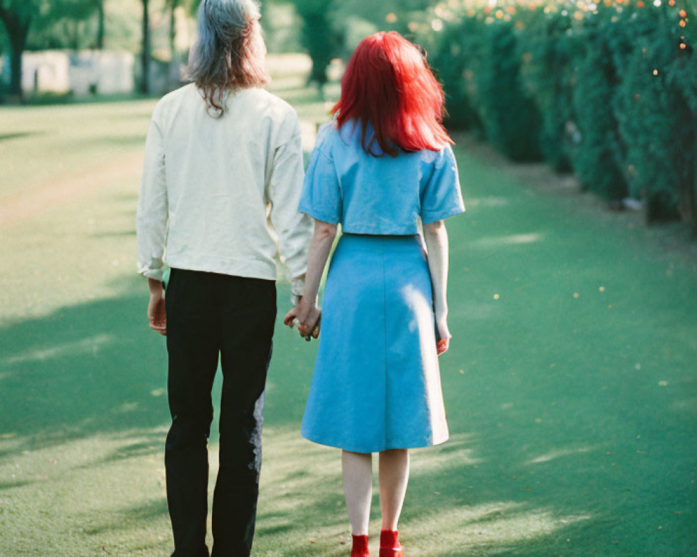 Elderly couple walking hand in hand on tree-lined path