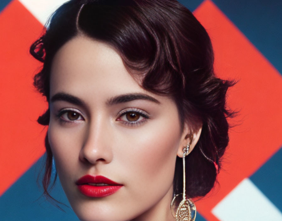 Dark-haired woman with hazel eyes and red lipstick on blue and red backdrop