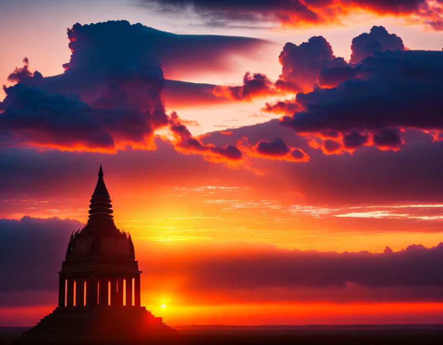 Pagoda silhouette against vibrant sunset sky with dramatic clouds.