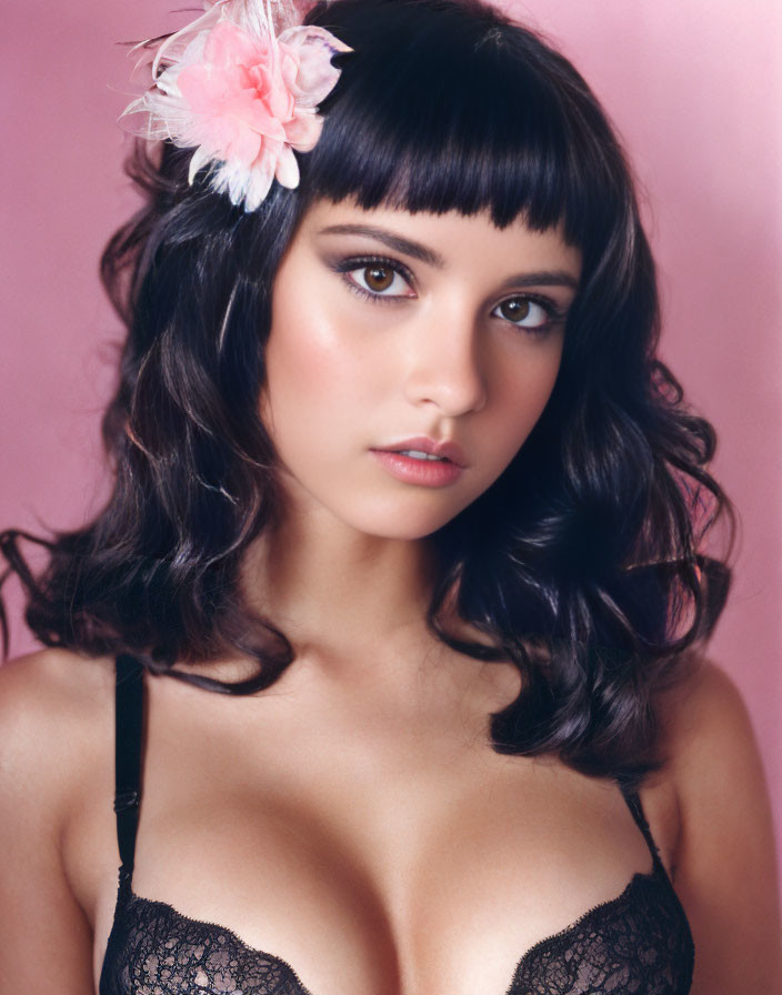 Dark-haired woman with bangs in black lace attire on pink background