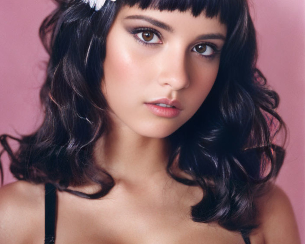 Dark-haired woman with bangs in black lace attire on pink background