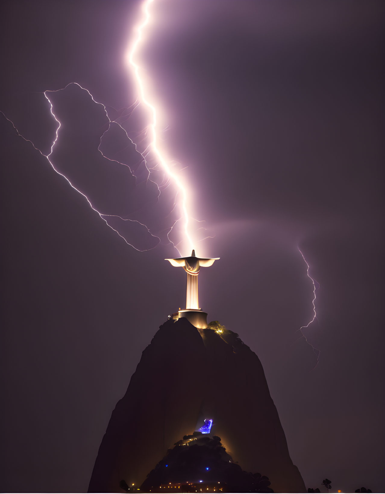 Giant illuminated statue on hilltop with lightning bolts in night sky