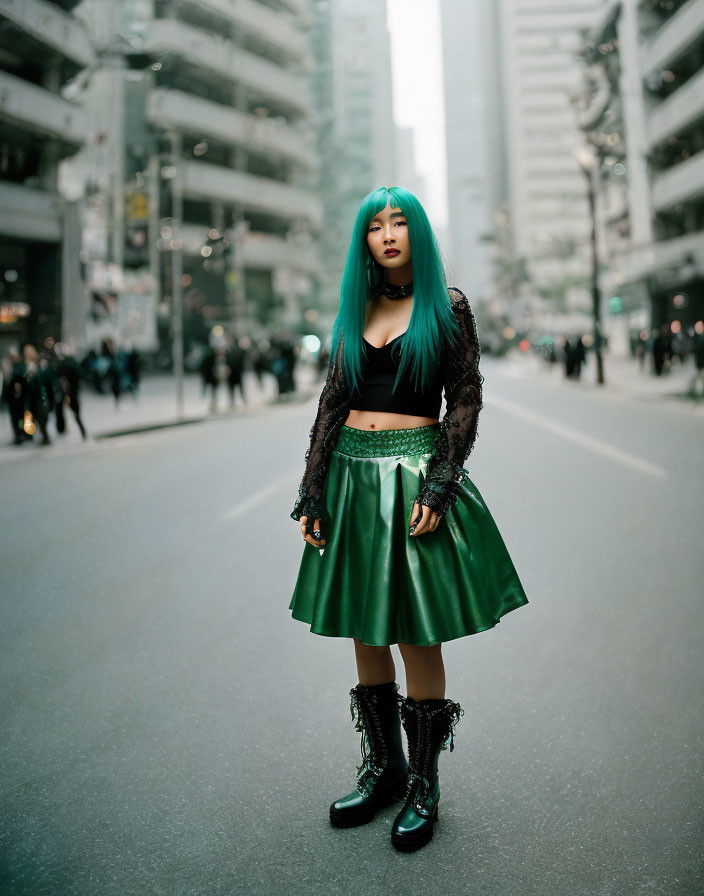 Turquoise-haired woman in city street with black top and green skirt