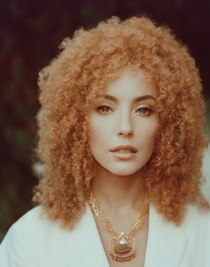 Curly-haired woman in white jacket with statement necklace