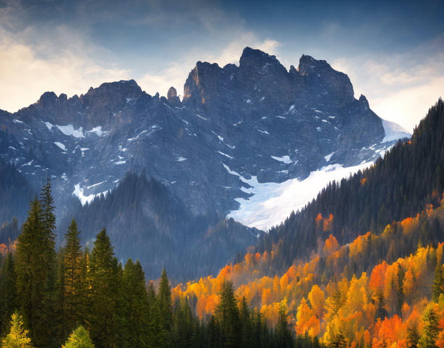 Snow-capped mountain peaks over autumn forest with vibrant foliage