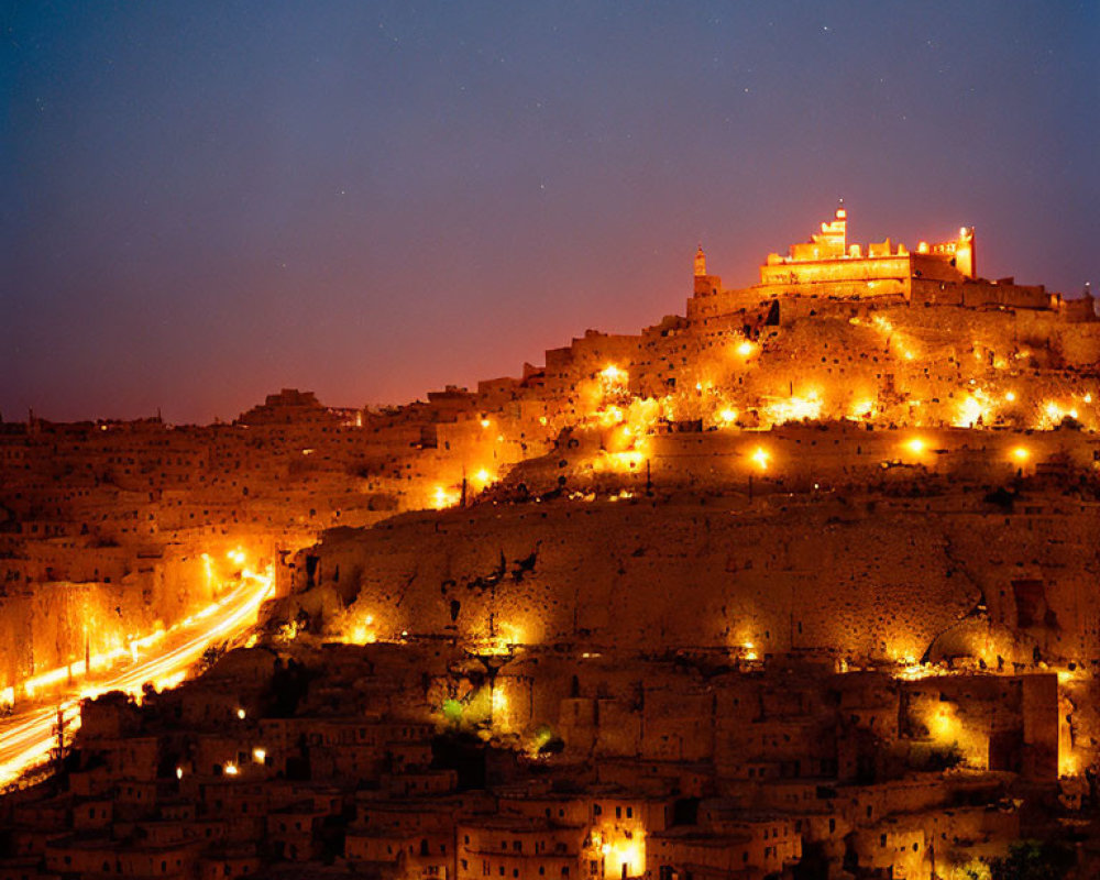 Hilltop fortress illuminated at night overlooking cityscape