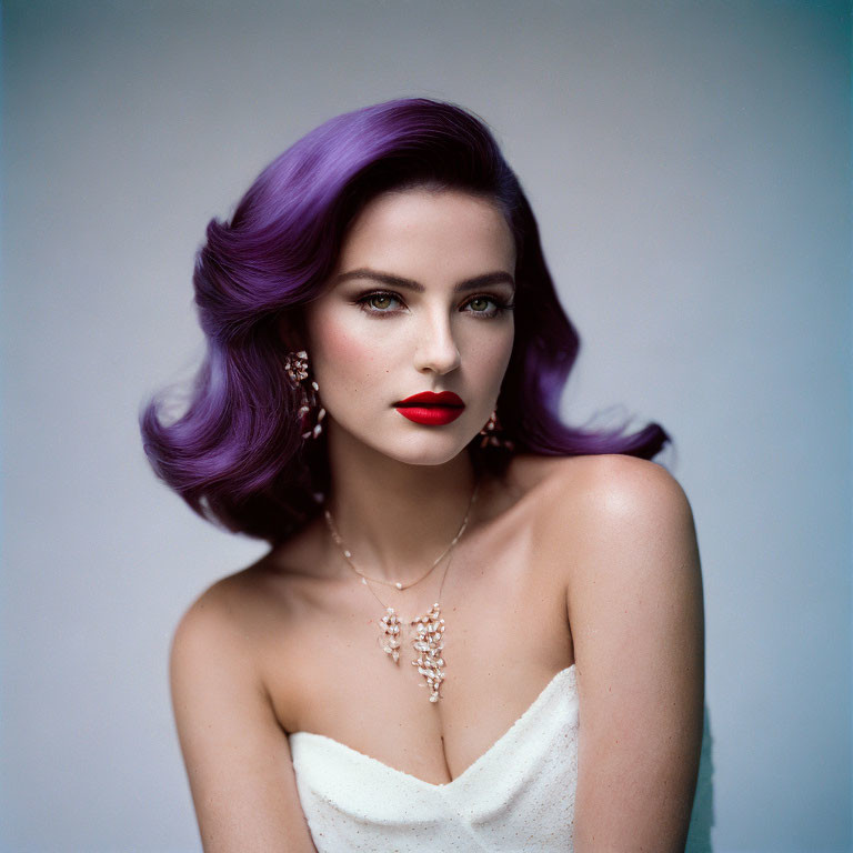 Purple-haired woman in red lipstick wears white dress and necklace on plain background