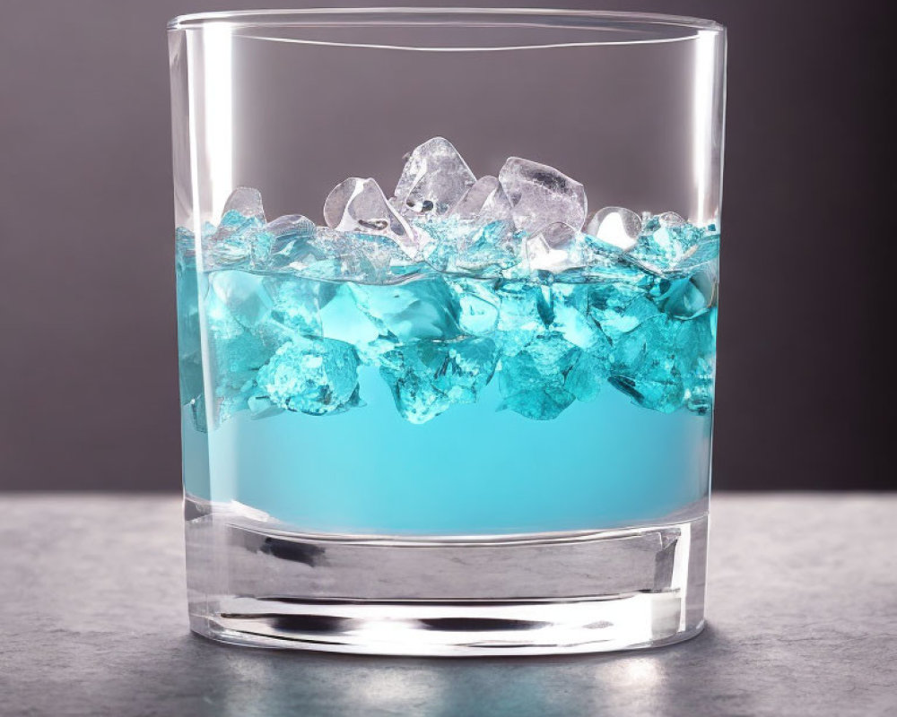 Glass of blue liquid and ice cubes on grey background