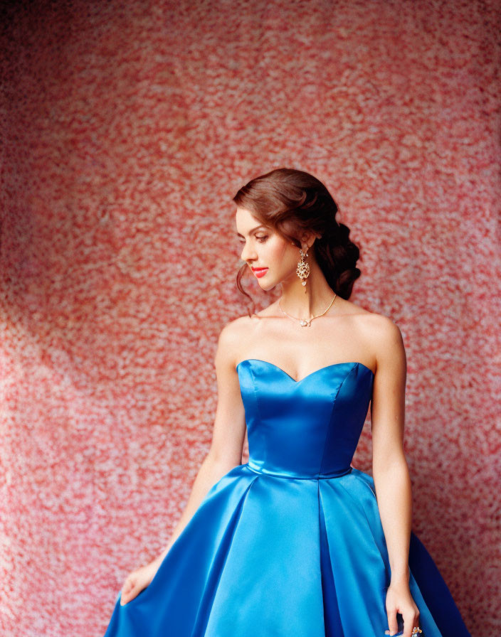 Woman in Strapless Blue Gown with Updo Hairstyle on Pink Background