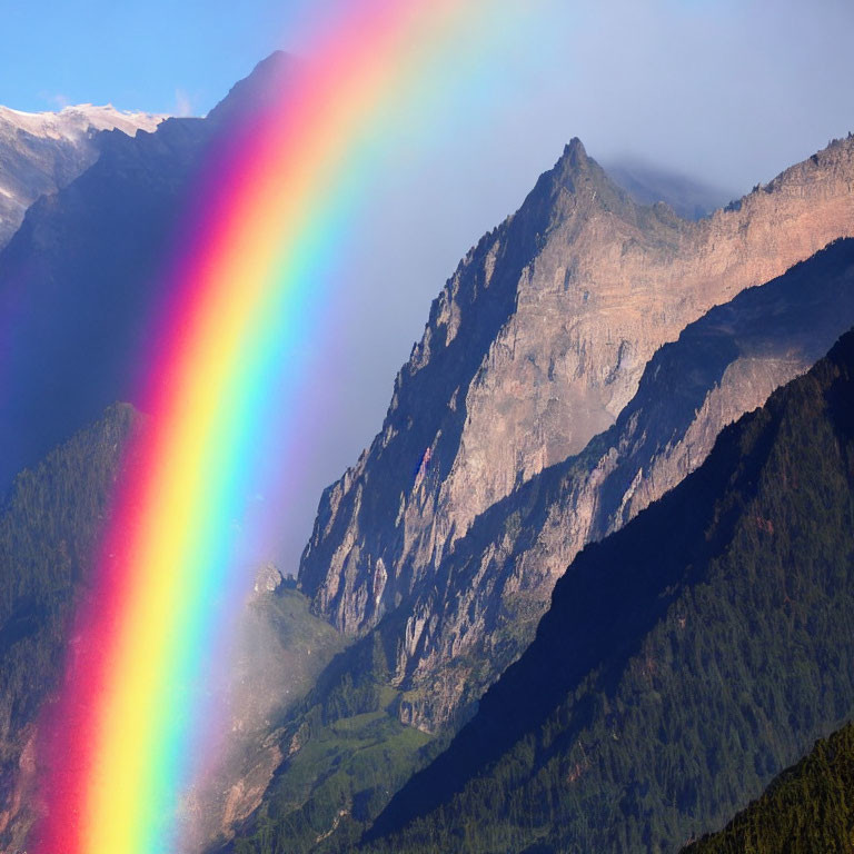 Colorful rainbow over cloudy mountain in sunlight