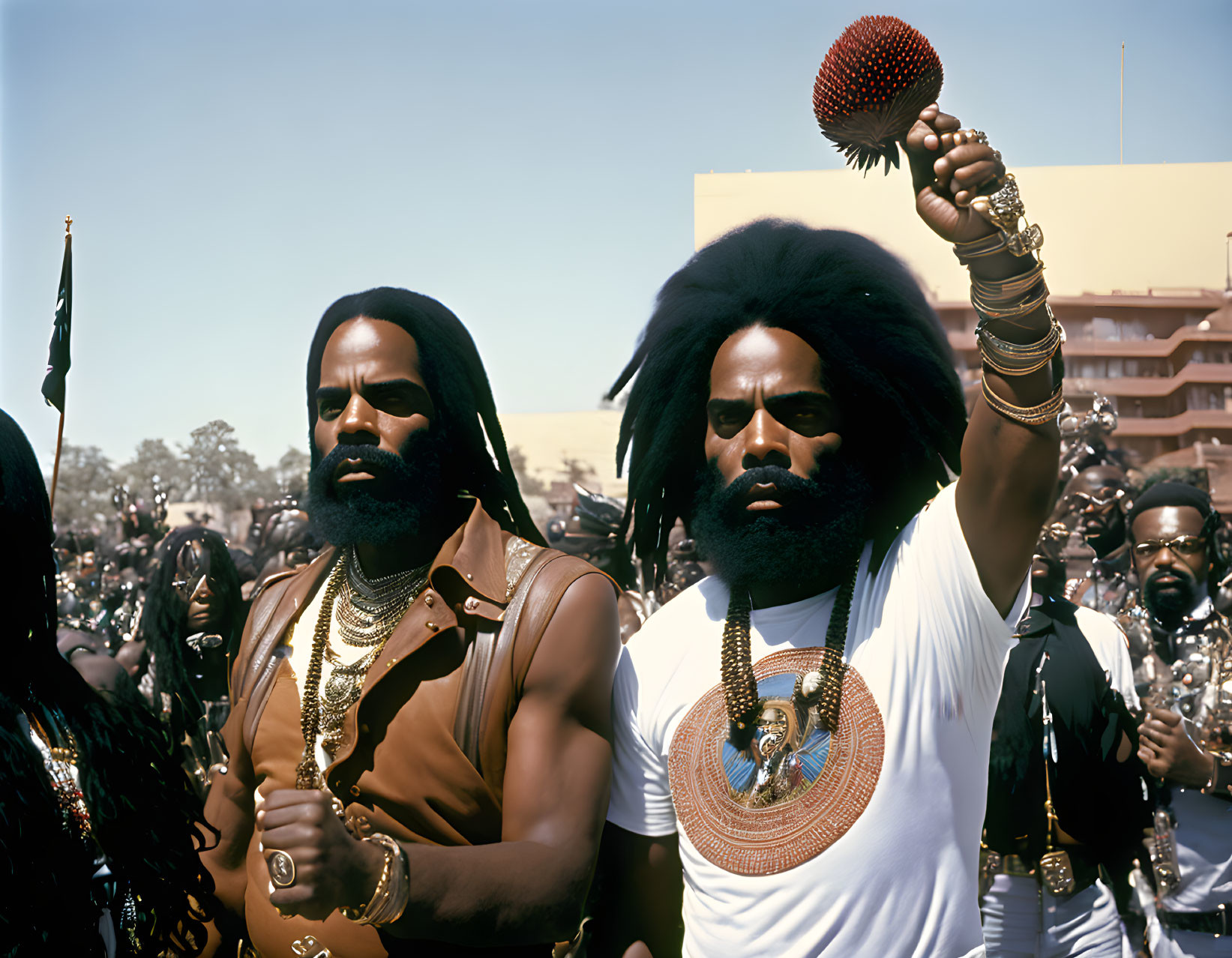 Men with beards and afros in parade with golden necklaces and staffs, surrounded by others