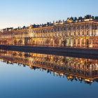 Palatial building with domes reflecting on calm water at dusk