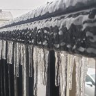 Frozen icicles with suspended water droplets and blurred winter landscape