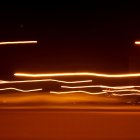 Long-exposure photo of golden light trails in dark starry sky