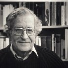 Elderly man with wavy hair and glasses smiling in monochrome photo