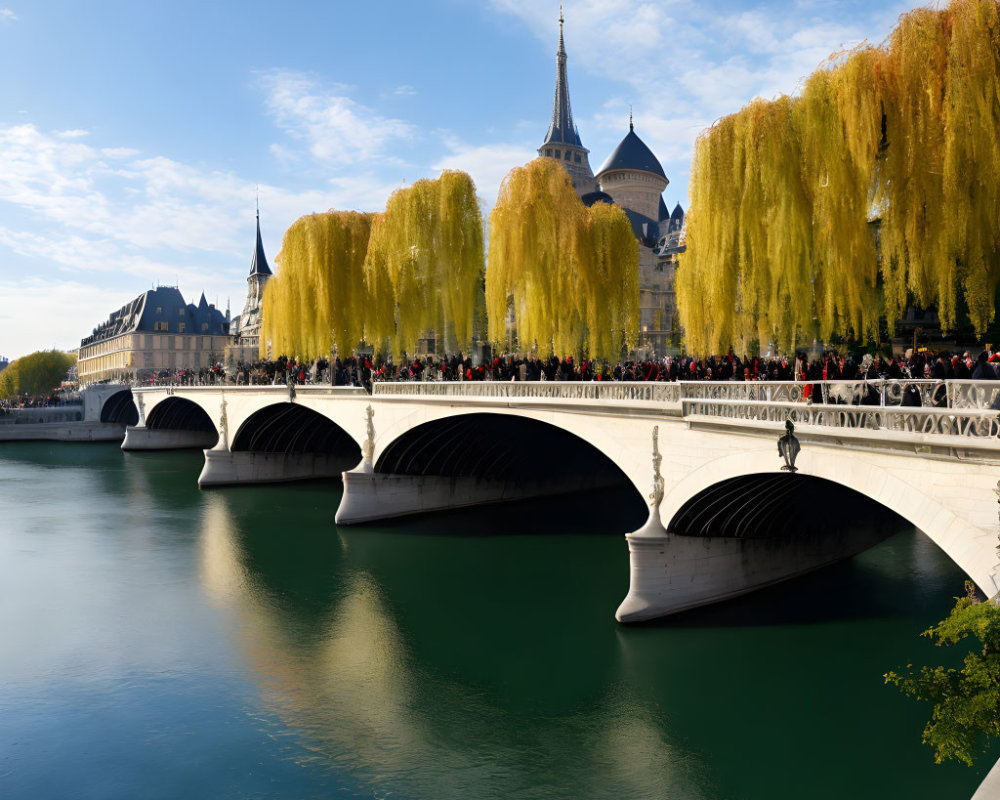 Scenic bridge over calm river with yellow trees and classic architecture.