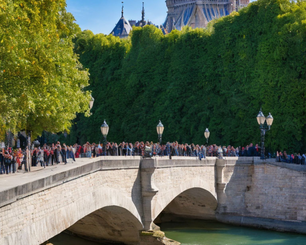 Stone bridge over river with pedestrians, green trees, historical building.