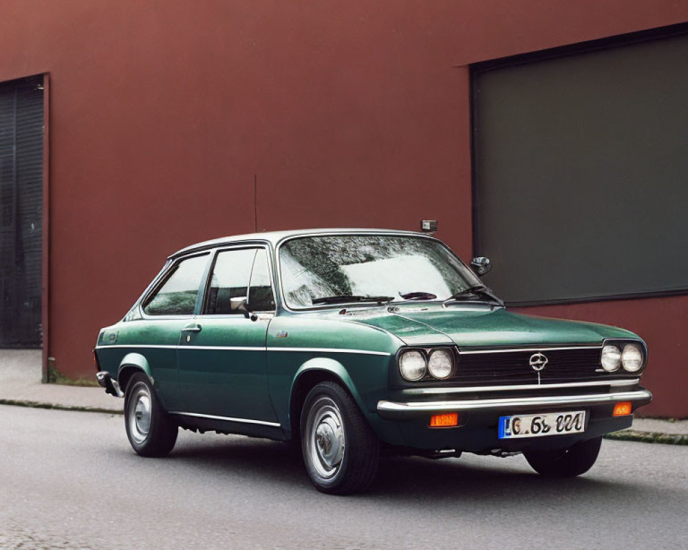 Vintage Green Opel Car Parked on Street with Red Wall and Dark Grey Garage Door