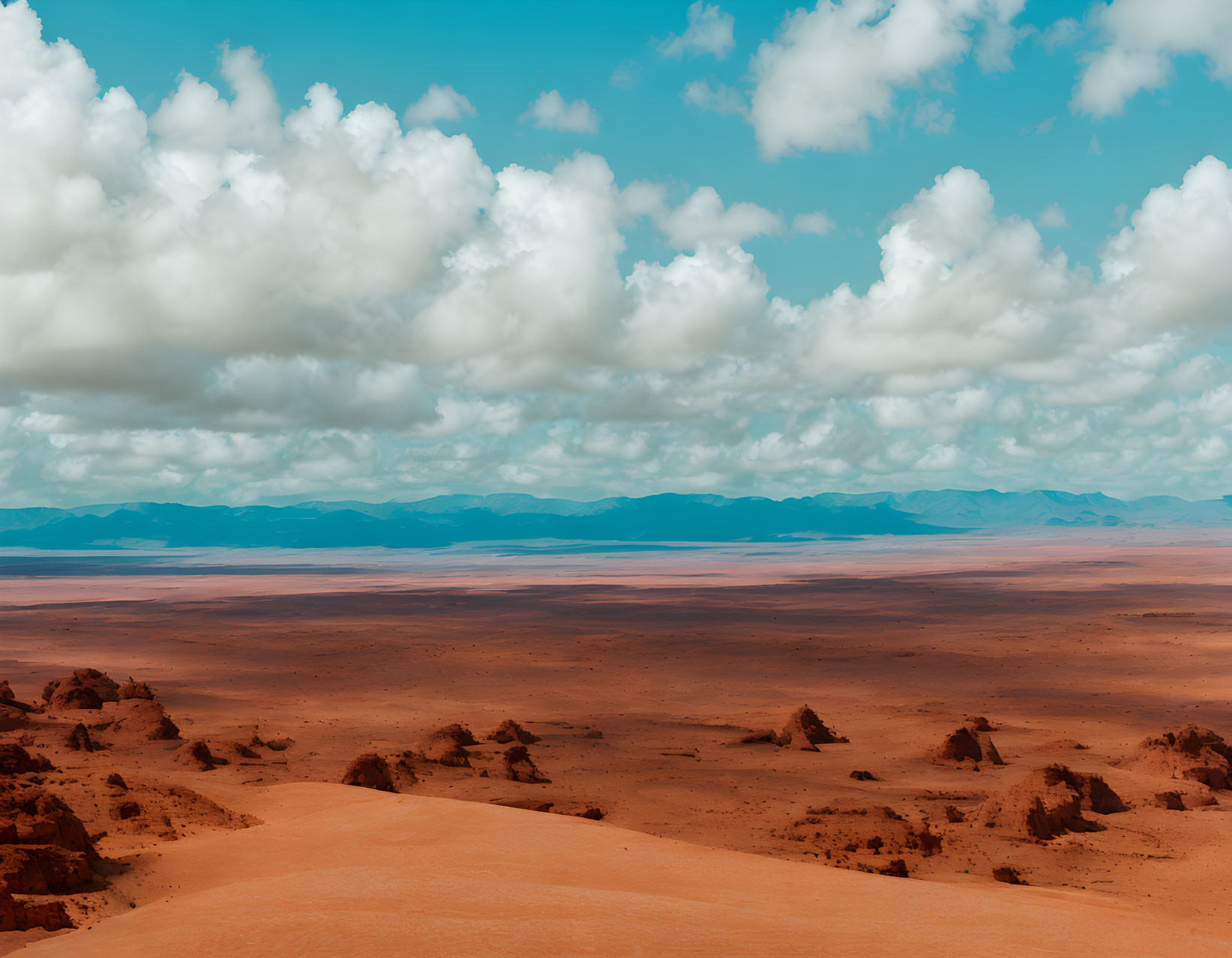 Orange Sand Desert Landscape with Rock Formations and Blue Sky