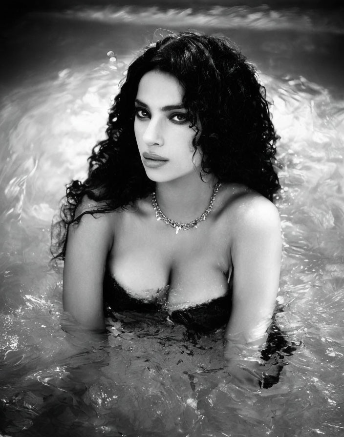 Monochrome portrait of woman with curly hair and necklace in water