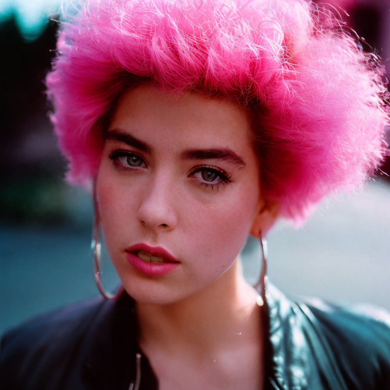 Vibrant pink-haired woman with hoop earrings gazes at the camera