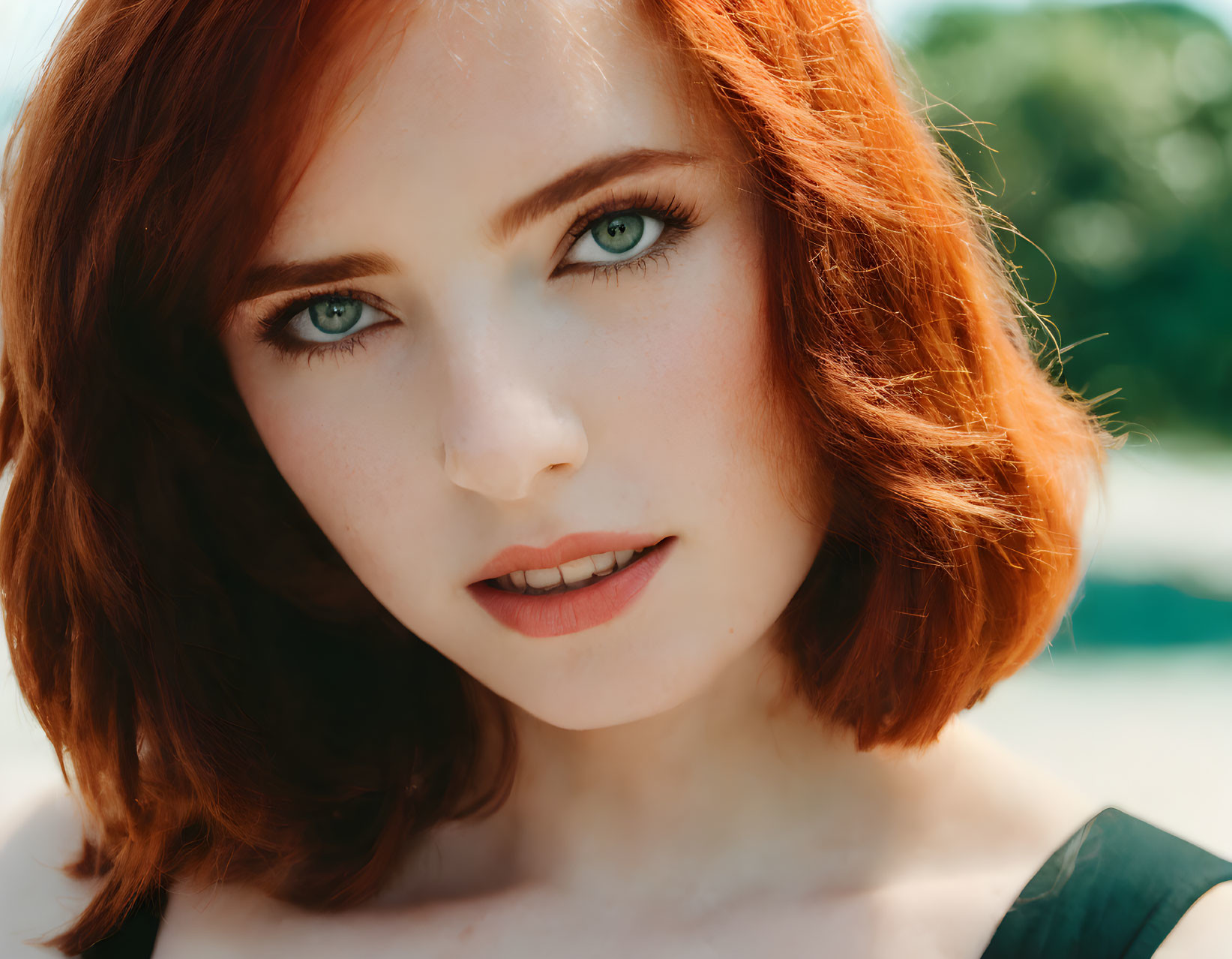 Portrait of Woman with Red Hair and Green Eyes on Blurred Green Background