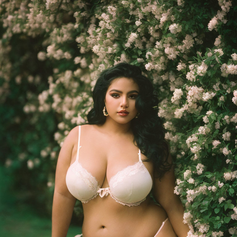 Woman in White Lingerie Posing in Lush Bushes with Pale Pink Flowers