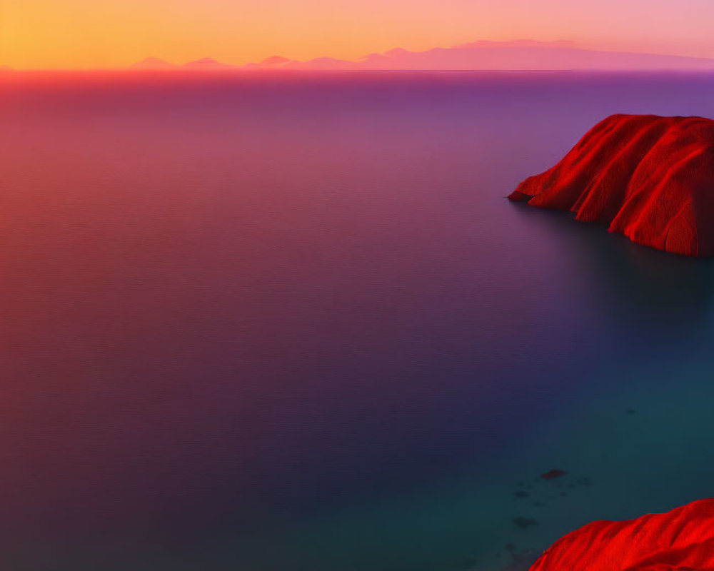 Colorful sunset over sea with mountain silhouettes and red hill.