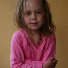 Young girl in pink sweater holding sparkly object surrounded by ethereal lights and planet image