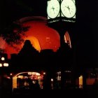 Night photo of building with red glow and green-lit clocks under dark sky